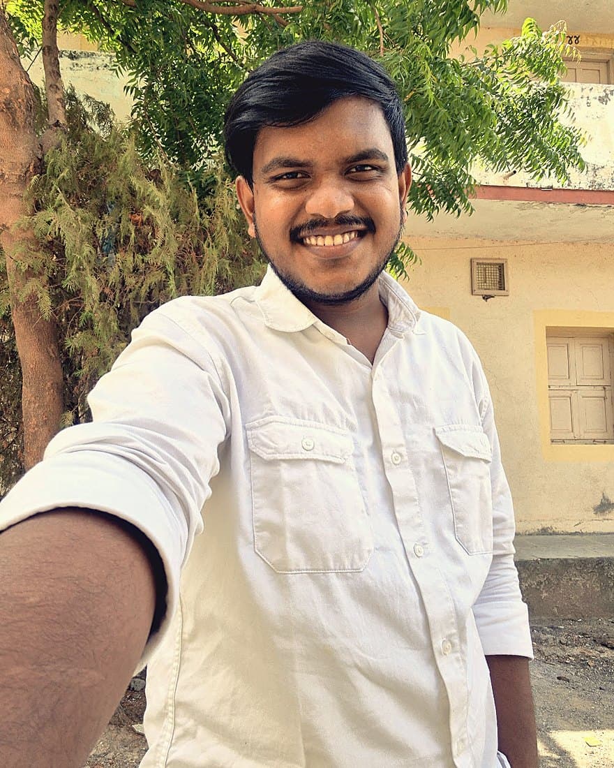 Meet Mistry smiling, outdoors in a white shirt